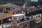 In a solemn, worldless ceremony marking wight months of cleanup from the terrorist attacks of September 11, 2001, which destroyed the twin towers of the World Trade Center, an empty stretcher is carried up the ramp from the pit, and the last steel column is carried out on a truck. An honor guard of police, firefighters, contruction workers, rescue personnel, and military lined the ramp. Families of victims were present as was Mayor Michael Bloomberg.