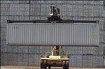 Shipping containers piled high in depots near ports in the U.S.A. illustrate America's trade deficit. Near Port Newark, New Jersey, container depots use special equipment to stack containers up to eight (8) high. Trucks drop off empty containers for storage or pick up empty ones for use. Depots resemble cities or monuments, blocking the skylines of Newark, N.J., and New York City.