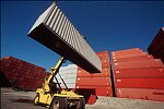 Shipping containers piled high in depots near ports in the U.S.A. illustrate America's trade deficit. Near Port Newark, New Jersey, container depots use special equipment to stack containers up to eight (8) high. Trucks drop off empty containers for storage or pick up empty ones for use. Depots resemble cities or monuments, blocking the skylines of Newark, N.J., and New York City.