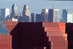 Shipping containers piled high in depots near ports in the U.S.A. illustrate America's trade deficit. Near Port Newark, New Jersey, container depots use special equipment to stack containers up to eight (8) high. Trucks drop off empty containers for storage or pick up empty ones for use. Depots resemble cities or monuments, blocking the skylines of Newark, N.J., and New York City.