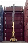 Shipping containers piled high in depots near ports in the U.S.A. illustrate America's trade deficit. Near Port Newark, New Jersey, container depots use special equipment to stack containers up to eight (8) high. Trucks drop off empty containers for storage or pick up empty ones for use. Depots resemble cities or monuments, blocking the skylines of Newark, N.J., and New York City.