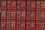 Shipping containers piled high in depots near ports in the U.S.A. illustrate America's trade deficit. Near Port Newark, New Jersey, container depots use special equipment to stack containers up to eight (8) high. Trucks drop off empty containers for storage or pick up empty ones for use. Depots resemble cities or monuments, blocking the skylines of Newark, N.J., and New York City.