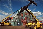 Shipping containers piled high in depots near ports in the U.S.A. illustrate America's trade deficit. Near Port Newark, New Jersey, container depots use special equipment to stack containers up to eight (8) high. Trucks drop off empty containers for storage or pick up empty ones for use. Depots resemble cities or monuments, blocking the skylines of Newark, N.J., and New York City.