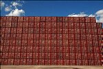 Shipping containers piled high in depots near ports in the U.S.A. illustrate America's trade deficit. Near Port Newark, New Jersey, container depots use special equipment to stack containers up to eight (8) high. Trucks drop off empty containers for storage or pick up empty ones for use. Depots resemble cities or monuments, blocking the skylines of Newark, N.J., and New York City.