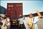 Shipping containers piled high in depots near ports in the U.S.A. illustrate America's trade deficit. Near Port Newark, New Jersey, container depots use special equipment to stack containers up to eight (8) high. Trucks drop off empty containers for storage or pick up empty ones for use. Depots resemble cities or monuments, blocking the skylines of Newark, N.J., and New York City.