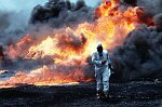 Al Ahmadi oilfields where wells set on fire by retreating Iraqi troops burn out of control. Michael Bailey takes samples for environmental testing. The skies are black wit soot.