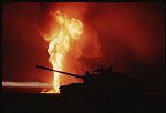  A destoyed Iraqi tank is silhouetted by a burning oil well in Kuwait, 1991