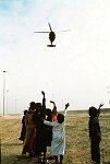 U.S. troops check I.D.'s of Arabs outside Safwan, Iraq, on the Kuwait City-Basra road.<br>Iraqi kids wave at U.S. helicopter