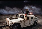 Al Ahmadi oilfields where wells set on fire by retreating Iraqi troops burn out of control. U.S. troops patrol the fields in a Humvee. The skies are black wit soot.
