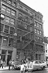 Performance artists dangle from a SoHo fire escape<br><br>From SoHo Blues - A Personal Photographic Diary of New York City in the 1970s by SoHo Weekly News chief photographer Allan Tannenbaum