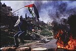 A Palestinian youth leaps onto a burning barricade in Nablus during the Intifada in 1988.