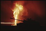 A destoyed Iraqi tank is silhouetted by a burning oil well in Kuwait, 1991